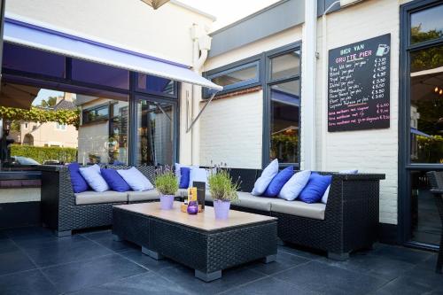 a patio with two couches and a table with blue pillows at Van der Valk Hotel Hardegarijp - Leeuwarden in Hardegarijp