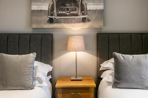 a bedroom with two beds and a table with a lamp at The Lodge @ Carus Green in Kendal