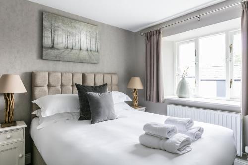 a bedroom with a large white bed with towels on it at The Lodge @ Carus Green in Kendal