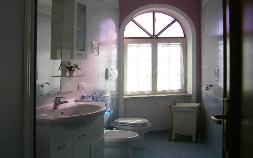 uma casa de banho com um lavatório, um WC e uma janela. em Villa En Rose em Ravello