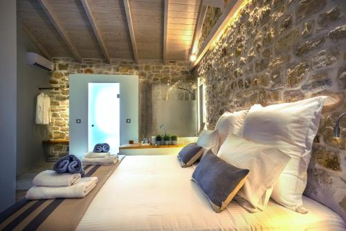 a bedroom with a bed with pillows and a stone wall at Paxos Fairytales Lovenest 2 in Gaios