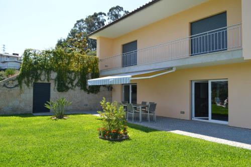 a house with a yard with a table and a balcony at AL Ribeiro in Póvoa de Lanhoso