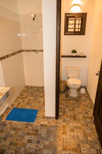 a bathroom with a toilet and a blue rug at Cabañas Amaia in Mazunte