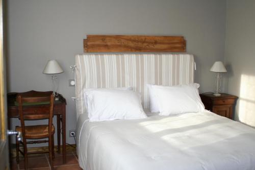 a bedroom with a white bed with a desk and a chair at Gîte de la Commanderie in Châtenay