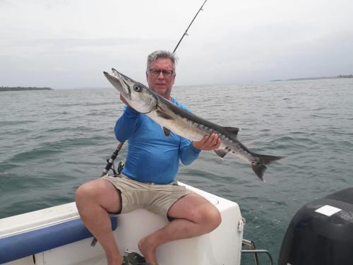 a man sitting on a boat holding a fish at Carmen's place in Bastimentos