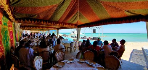 a group of people sitting at tables on the beach at Hôtel Calipau Riad Maison d'Hôtes in Dakhla