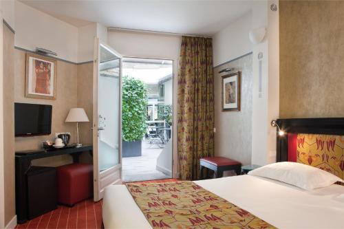 Pokój hotelowy z łóżkiem i przesuwnymi szklanymi drzwiami w obiekcie Hotel Eiffel Seine w Paryżu