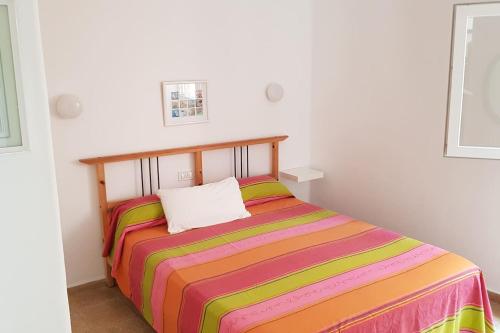 - une chambre avec un lit et une couverture rayée colorée dans l'établissement Surfing the Blue I, à Punta del Hidalgo