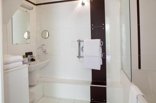 a white bathroom with a shower and a sink at Hotel Eiffel Seine in Paris