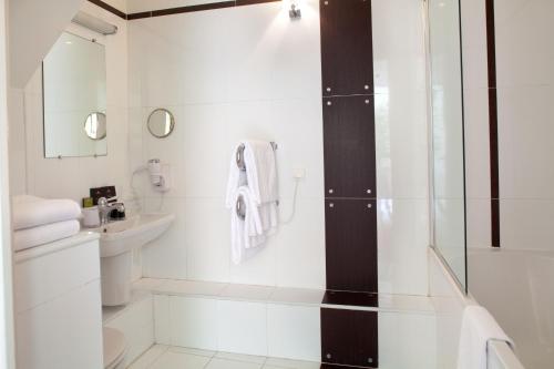 a white bathroom with a shower and a sink at Hotel Eiffel Seine in Paris