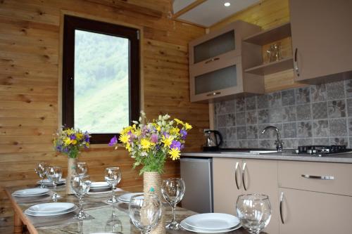 uma cozinha com uma mesa com copos e flores em Gergeti Woods em Stepantsminda