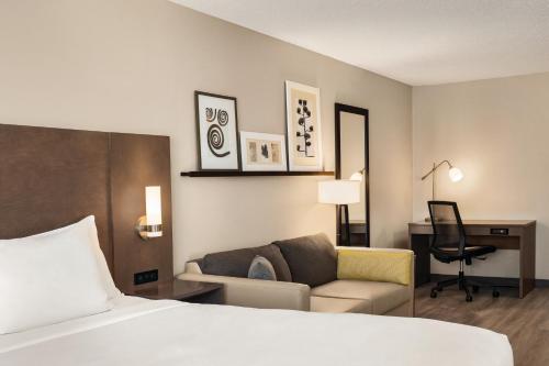 バッファローにあるCountry Inn & Suites by Radisson, Buffalo, MNのベッド、ソファ、デスクが備わるホテルルームです。