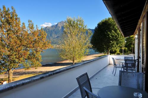a balcony with tables and chairs and a view of a lake at Villa Carolina in Domaso