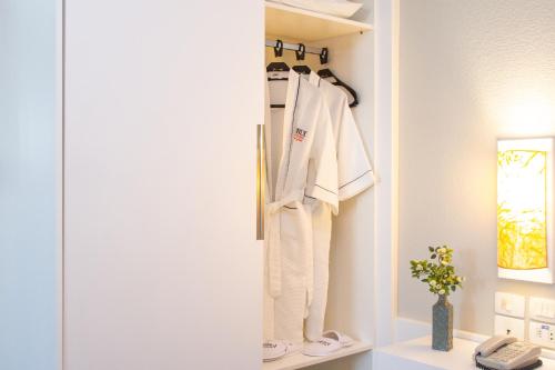 a closet with white clothes hanging on a wall at Bristol Brasil 500 Curitiba Batel in Curitiba