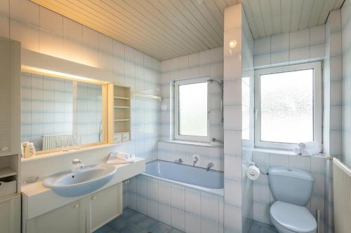 uma casa de banho com uma banheira, um lavatório e um WC. em Das Talblick - Appartments em Sankt Johann im Pongau