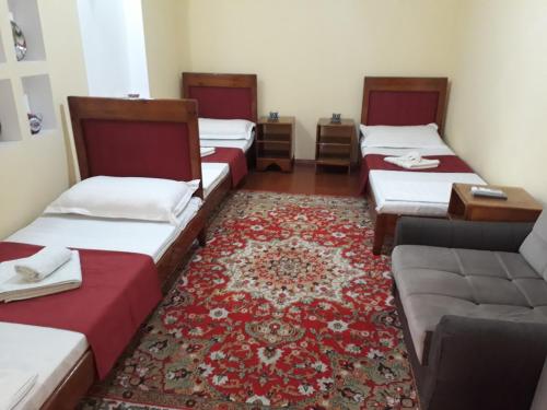 een kamer met vier bedden en een bank en een tapijt bij Amir-Yaxyo Hotel in Bukhara