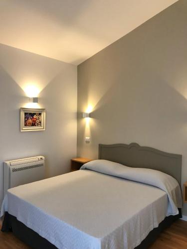 a bedroom with a bed and two lights on the wall at Cinema House Apartments in Orbetello