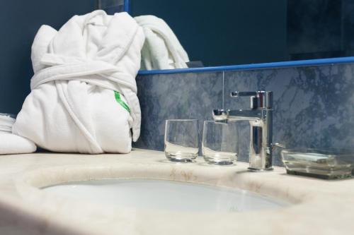 a bathroom sink with two glasses and a towel at Hotel Mamiani & Relaxing Spa Urbino in Urbino