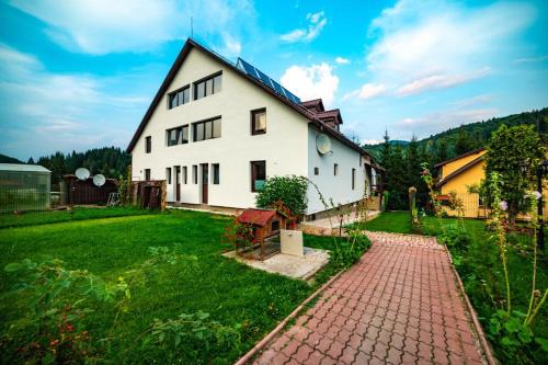 a large white house with a brick path in a yard at Poiana Cristian in Poiana Brasov
