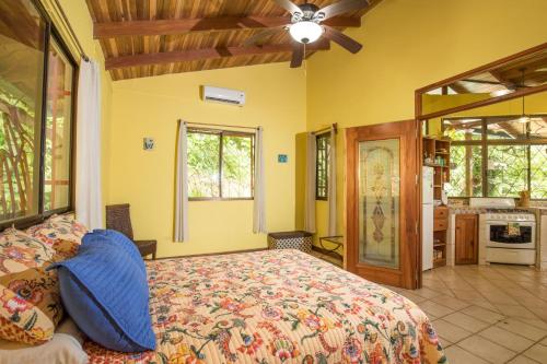 a bedroom with a large bed and a kitchen at Kiskadee Casa in Quepos