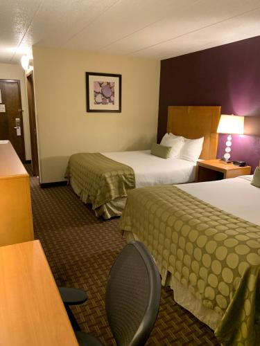 a hotel room with two beds and a desk at Ramada by Wyndham Marquette in Marquette