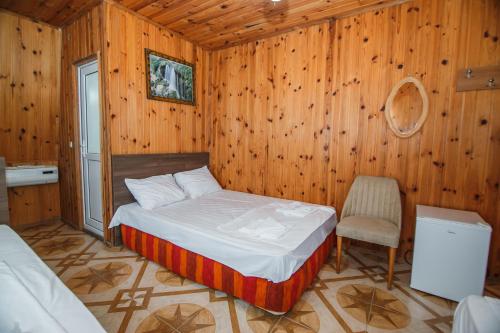 1 dormitorio con 1 cama, 1 silla y paredes de madera en Guest House Nia, en Gonio