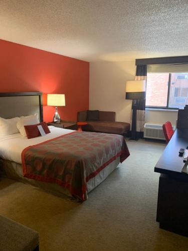 a hotel room with a large bed and a couch at Ramada by Wyndham Marquette in Marquette