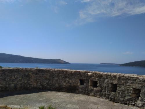 a stone wall with a view of the water at Studio Apartman GRACIJA in Herceg-Novi