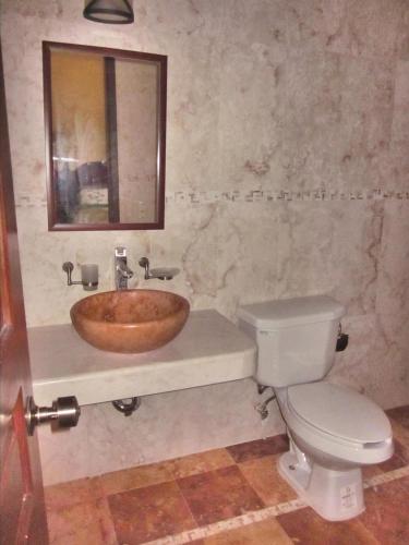 a bathroom with a wooden sink and a toilet at Casa de los Pianos in Uaymá