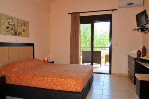 1 dormitorio con 1 cama y puerta que da a un patio en Golden Sunrise Apartments, en Chrysi Ammoudia