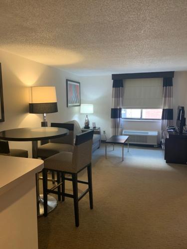 a hotel room with a living area with tables and chairs at Ramada by Wyndham Marquette in Marquette