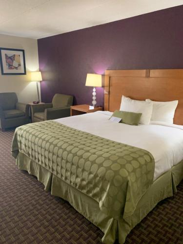 a hotel room with a large bed and a chair at Ramada by Wyndham Marquette in Marquette