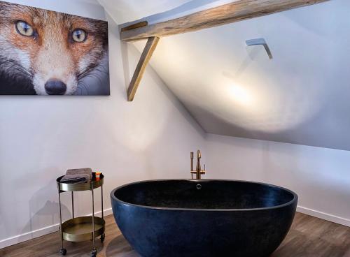 a bathroom with a large black tub in a attic at De Bonderbei in Wellen