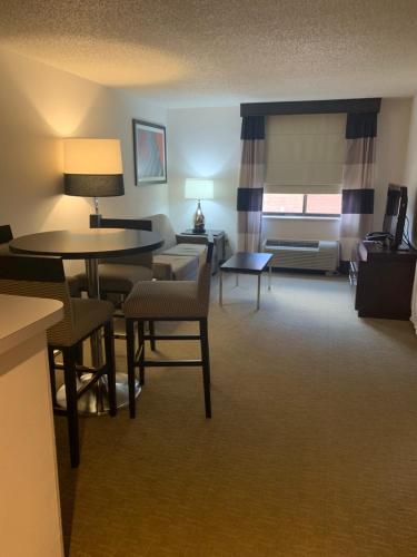 a hotel room with tables and chairs and a living room at Ramada by Wyndham Marquette in Marquette