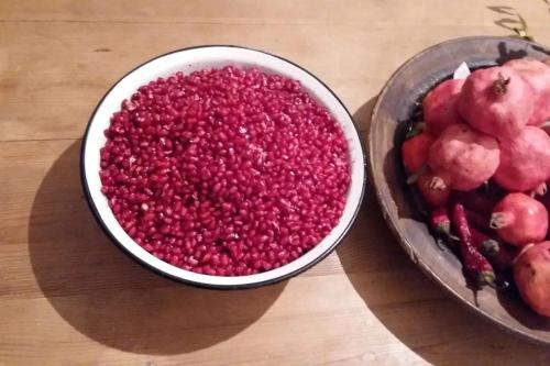 una ciotola di cibo rosso accanto a un cesto di frutta di Mzia's Garden a Kʼvakhvreli