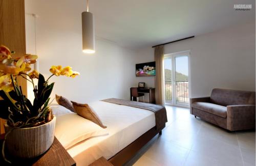 a bedroom with a bed and a chair and a vase with flowers at San Severino Park Hotel & SPA, BW Signature Collection in Mercato San Severino