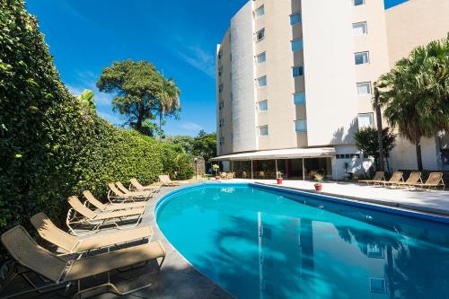 uma piscina com espreguiçadeiras ao lado de um edifício em Hotel Vila Rica Campinas em Campinas