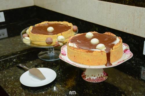 two cakes on plates on a counter with chocolate at Hotel São Bento in Marabá