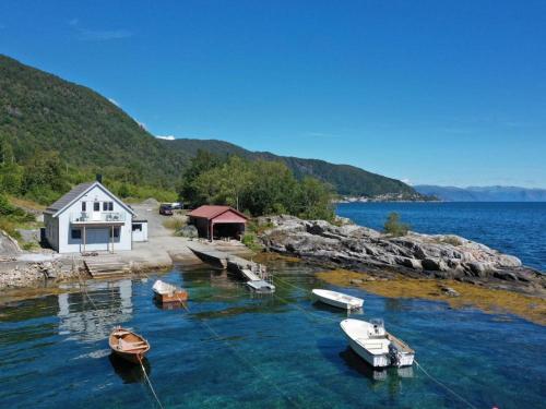 um grupo de barcos na água ao lado de uma casa em Waerholmen em Lavik