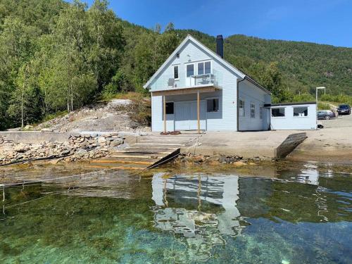 una casa bianca seduta accanto a un corpo d'acqua di Waerholmen a Lavik
