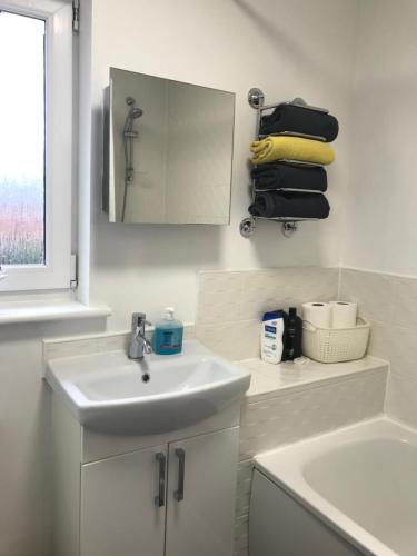 Baño blanco con lavabo y espejo en Hollybrae house Sleeps up to 6, en Kirkcaldy