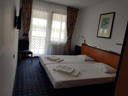 Una habitación de hotel con dos camas y una ventana. en Portul Dunarii, en Hîrşova
