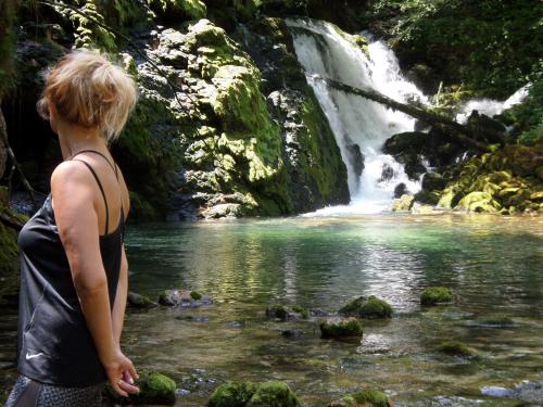 a woman standing in front of a waterfall at Snežak (Snowman) in Bohinj