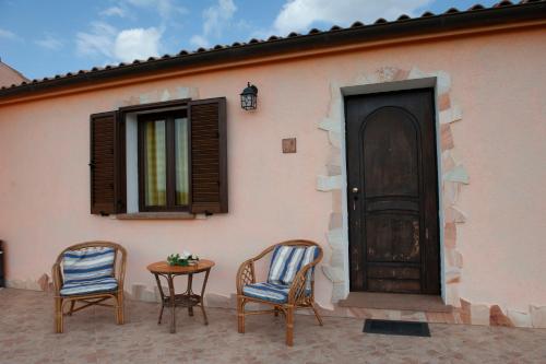 two chairs and a table in front of a house at Agriturismo B&B Casteldoria in Santa Maria