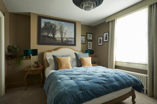 1 dormitorio con 1 cama con edredón azul y ventana en Broad Street Townhouse en Bath