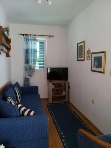 a living room with a blue couch and a tv at Apartmani Stipanic Tivat in Tivat