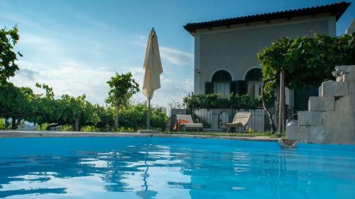 a swimming pool in front of a house with an umbrella at Il Casino di Donna Maria in Mormanno