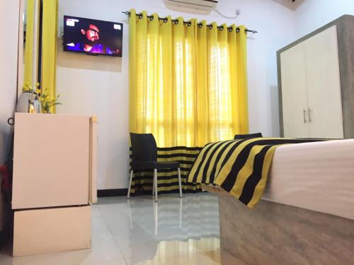 a bedroom with a bed and a yellow curtain at Villa Dominikku in Negombo