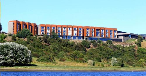 a building on top of a hill next to a body of water at Enjoy Chiloé in Castro