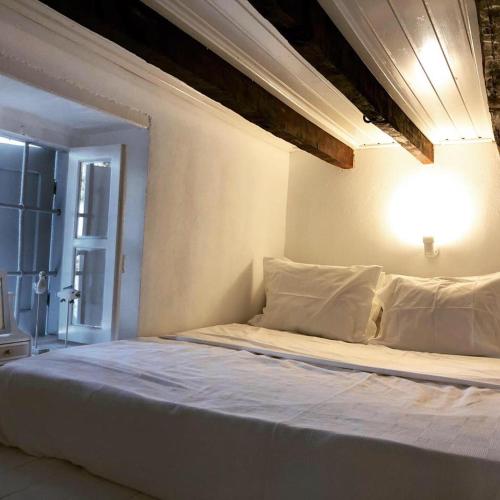 a white bed in a room with a light at The Pulse Residence Astypalea in Astypalaia
